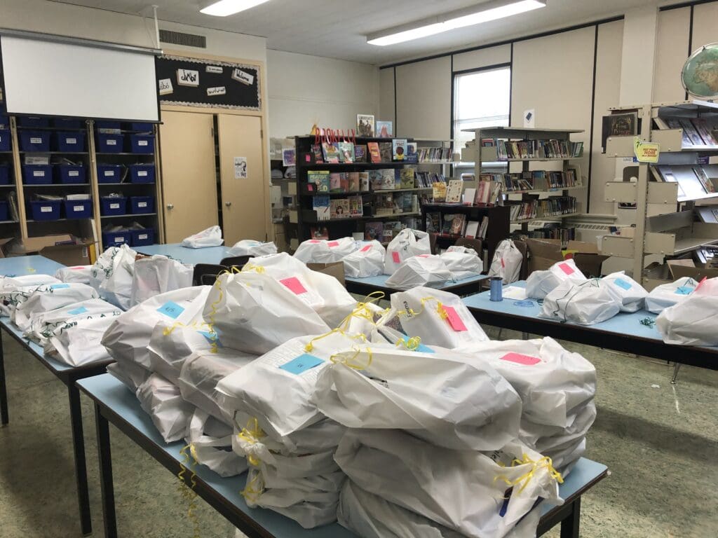 A library filled with white bags stuffed with donated books.